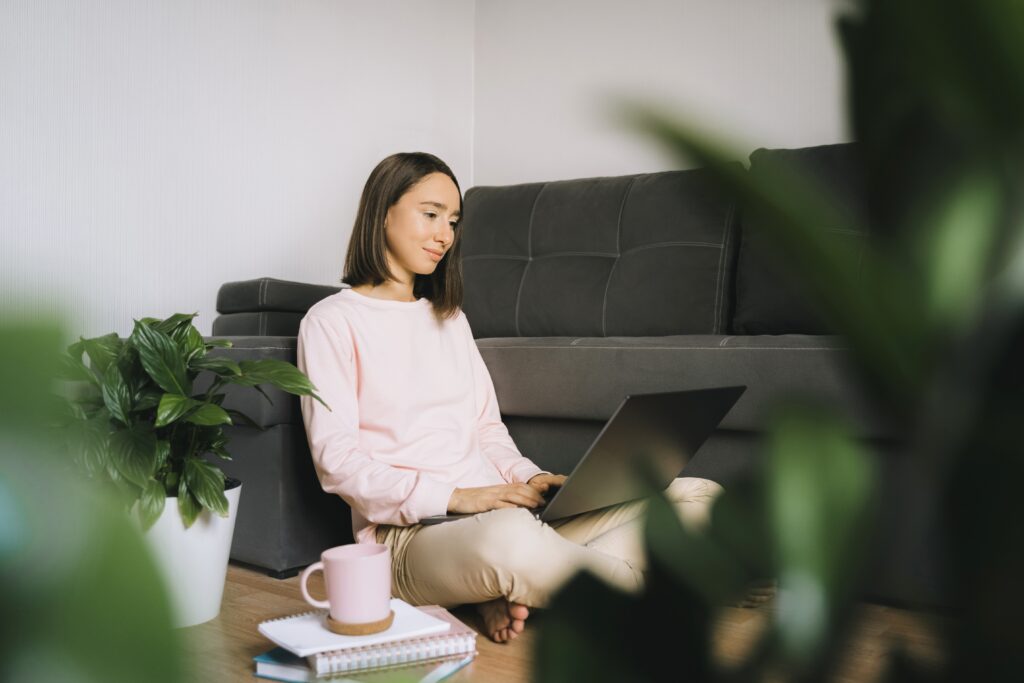 Young Woman Sitting On The Floor And Using Laptop.